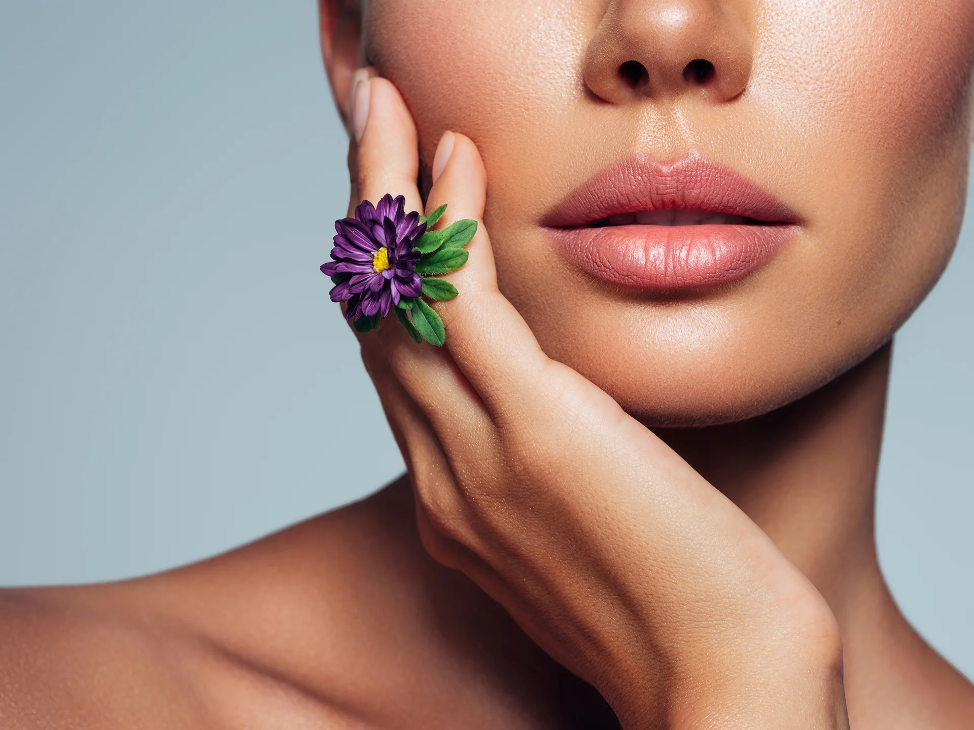 a portrait of woman with plump lips while holding a flower in her hand