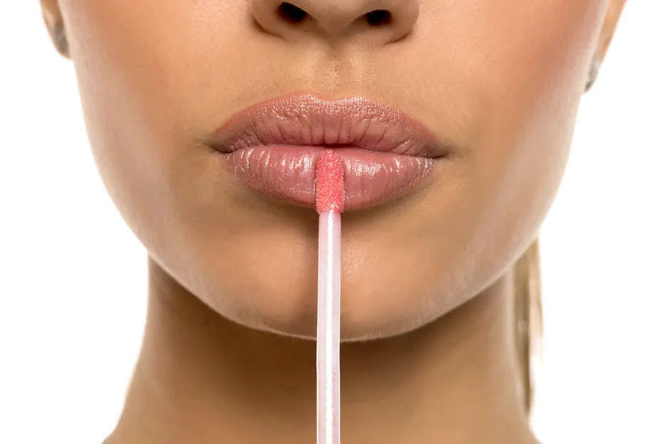 a woman applies lip plumper on her lips