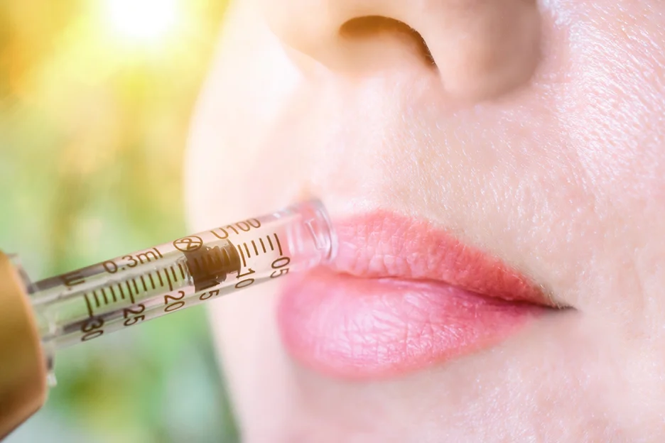 a woman uses hyaluron pen to plump her lips 