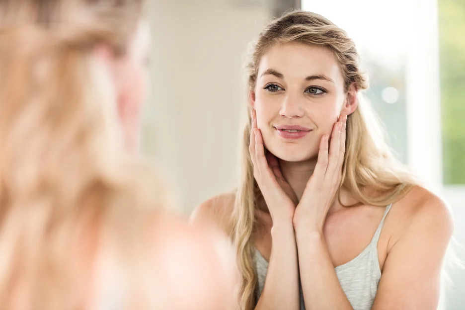 a woman checks herself in front of the mirror after subtle lip filler injections