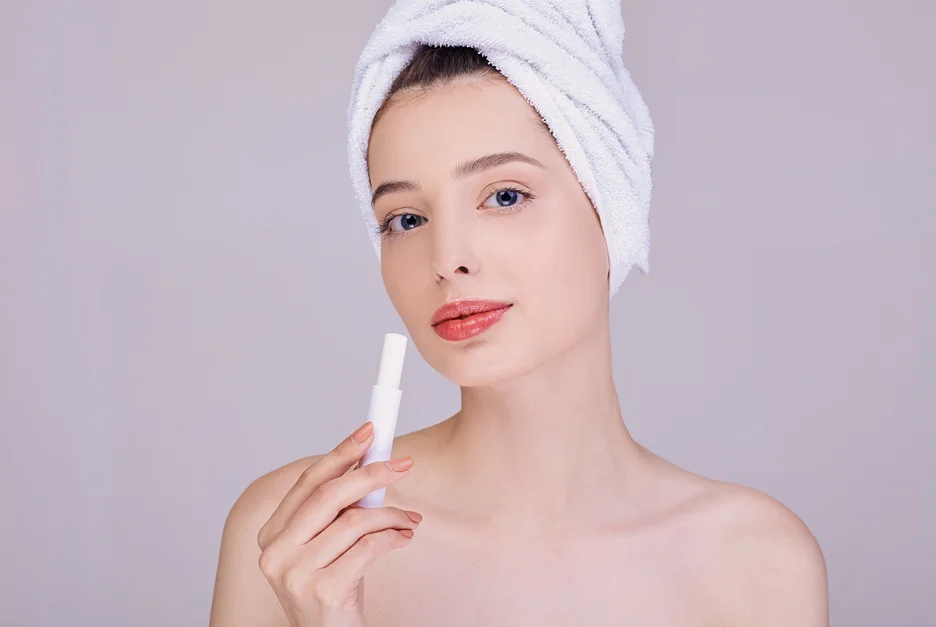 a woman is holding lip balm to hydrate her lips after shower