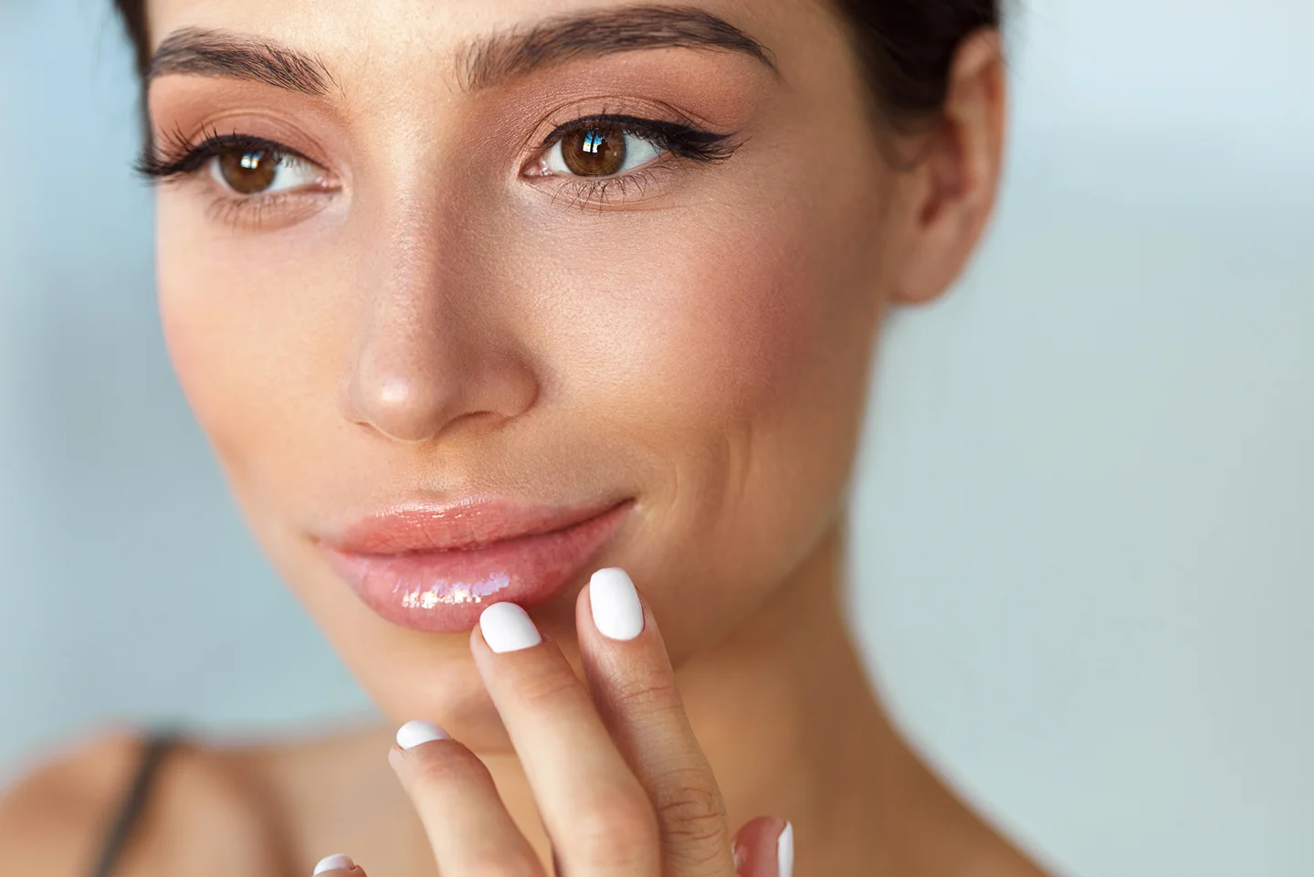 a woman touches her lips after lip filler treatments